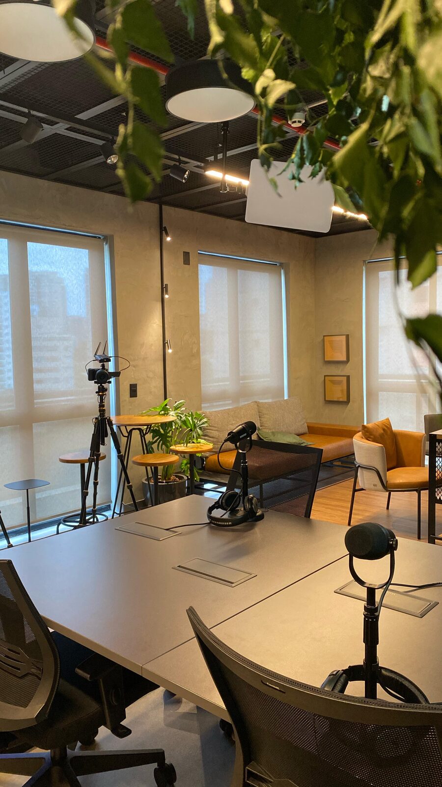 Sala de gravação com mesa, microfones e janelas