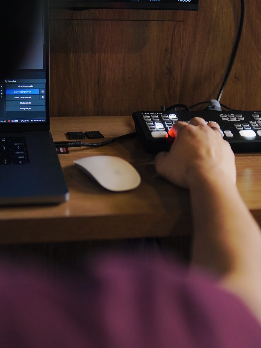 Detalhe de mão operando switcher com medidores de áudio
